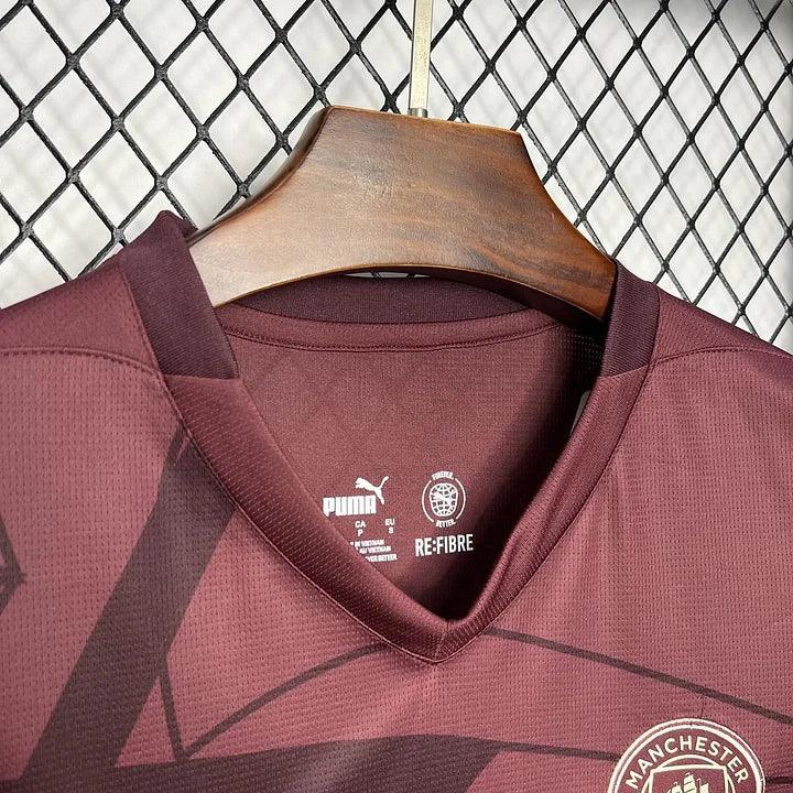 Maillot Manchester City 2024/25 Le 12 -ème Maillot, maillot de football bleu avec logo et détails officiels visible.