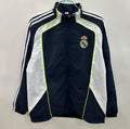 Veste coupe-vent réversible Real Madrid, marque Le 12 -ème Maillot, montrée pliée avec logo et détails de design.