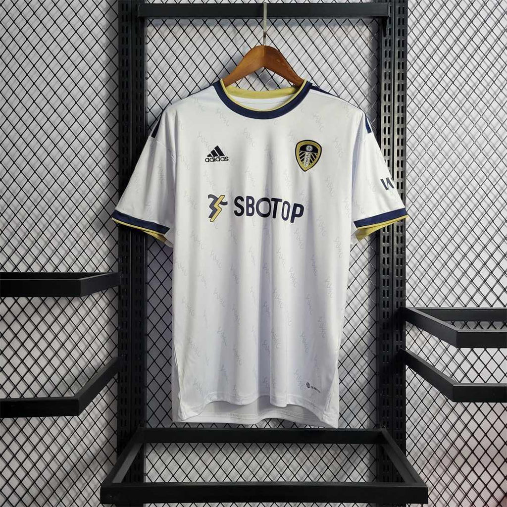 Maillot Leeds United 2022-23 Le 12 -ème Maillot, jersey de football blanc avec logo et détails bleus, porté par un joueur sur le terrain
