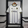 Maillot Leeds United 2022-23 Le 12 -ème Maillot, jersey de football blanc avec logo et détails bleus, porté par un joueur sur le terrain