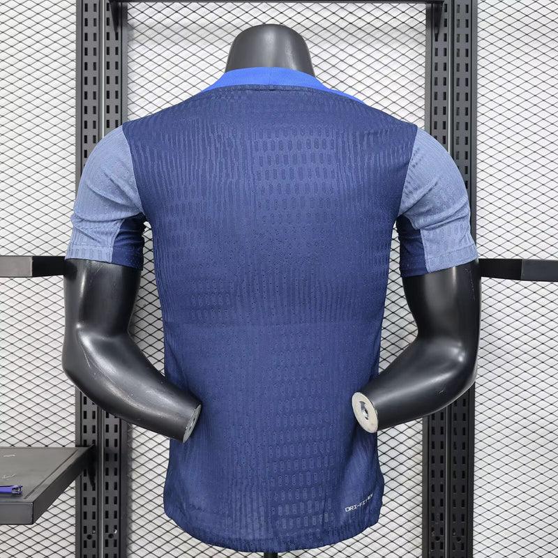Maillot d'entraînement PSG 2025-26 de la marque Le 12, tissu bleu avec logos et détails de l'équipe Paris Saint-Germain.
