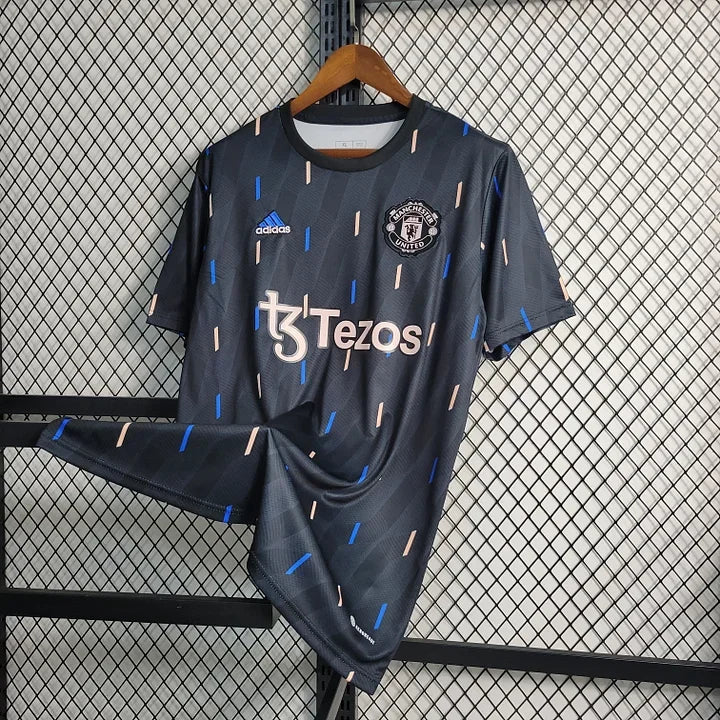 Maillot d'entraînement Manchester United 2023, marque Le 12-ème Maillot, en tissu bleu avec logo et détails de l'équipe.
