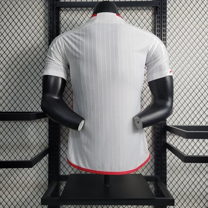 Maillot Manchester United 2023 2024 Le 12 -ème Maillot, maillot de football avec logo rouge et détails bleus sur fond blanc