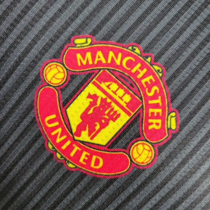 Maillot Manchester United Le 12 -ème Maillot 2023 2024, maillot de football rouge avec logo du club visible.