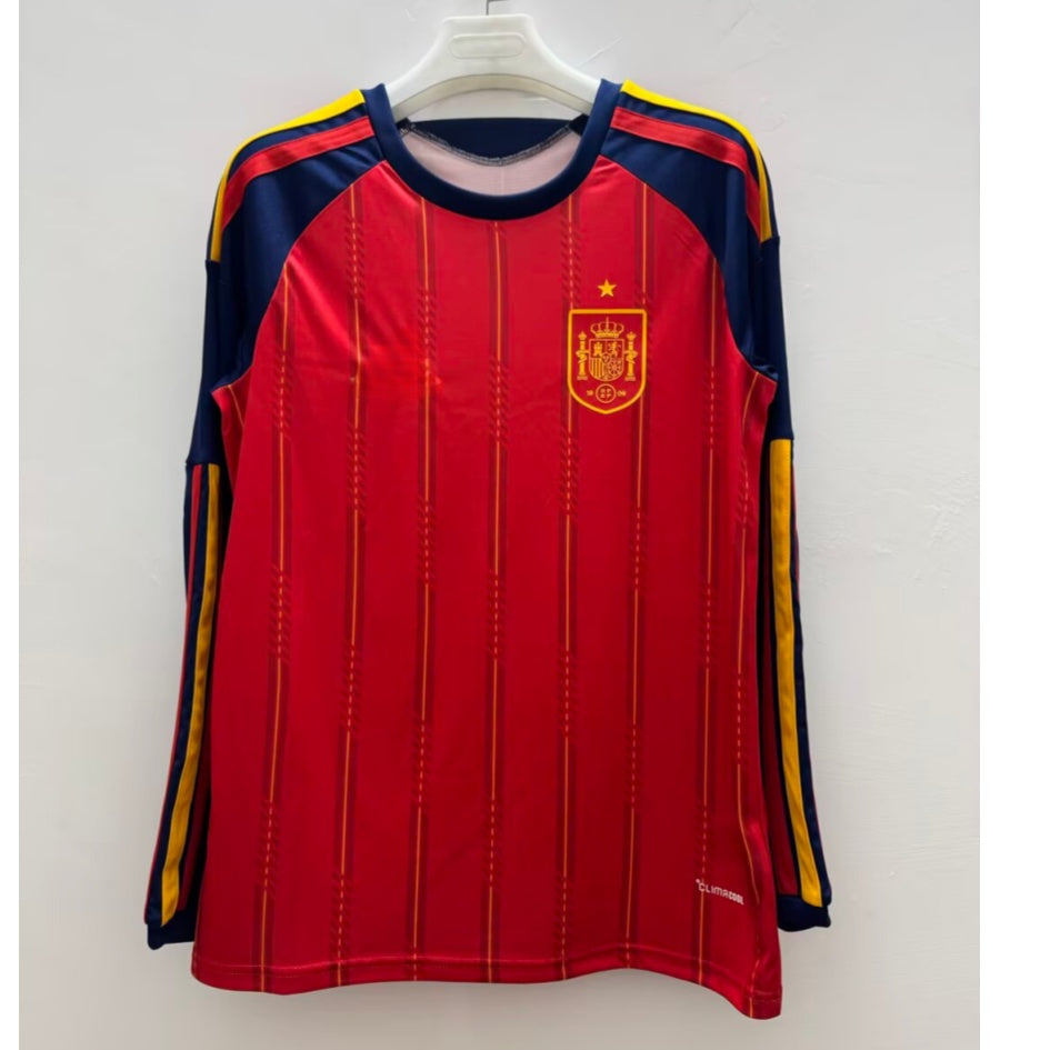 Maillot domicile Espagne 25/26 à manches longues, marque Le 12 -ème Maillot, avec logo et design rouge et jaune.