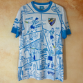 Maillot Malaga 25/26 Le 12 -ème Maillot, maillot de football avec logo et détails en bleu et blanc, vue de face.