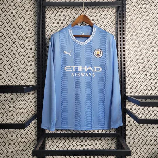 Maillot Manchester City 2023 2024 à manches longues, veste de football Le 12 -ème Maillot, logo et design bleu et blanc.