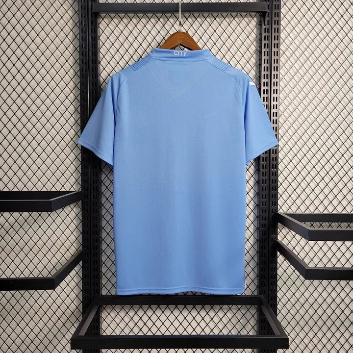 Maillot domicile Manchester City saison 2023-2024, marque Le 12 -ème Maillot, vue de face avec logo et détails bleus et blanc