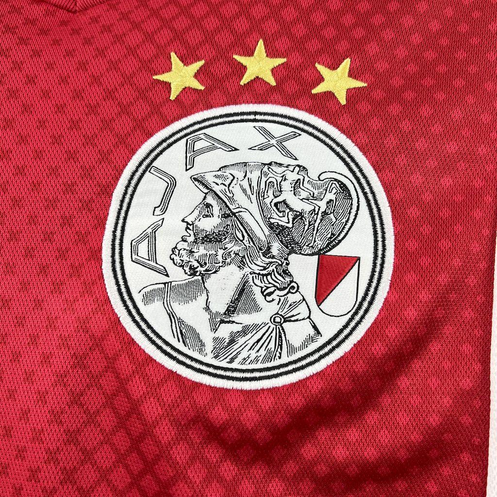 Maillot Ajax 2025-26 Le 12 -ème Maillot, maillot de football avec logo Ajax et design blanc et rouge visible sur l'image.
