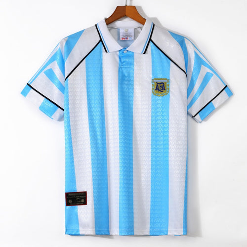Maillot domicile rétro de l'Argentine 1996-1997, marque Le 12, avec logo et détails colorés sur fond bleu clair.