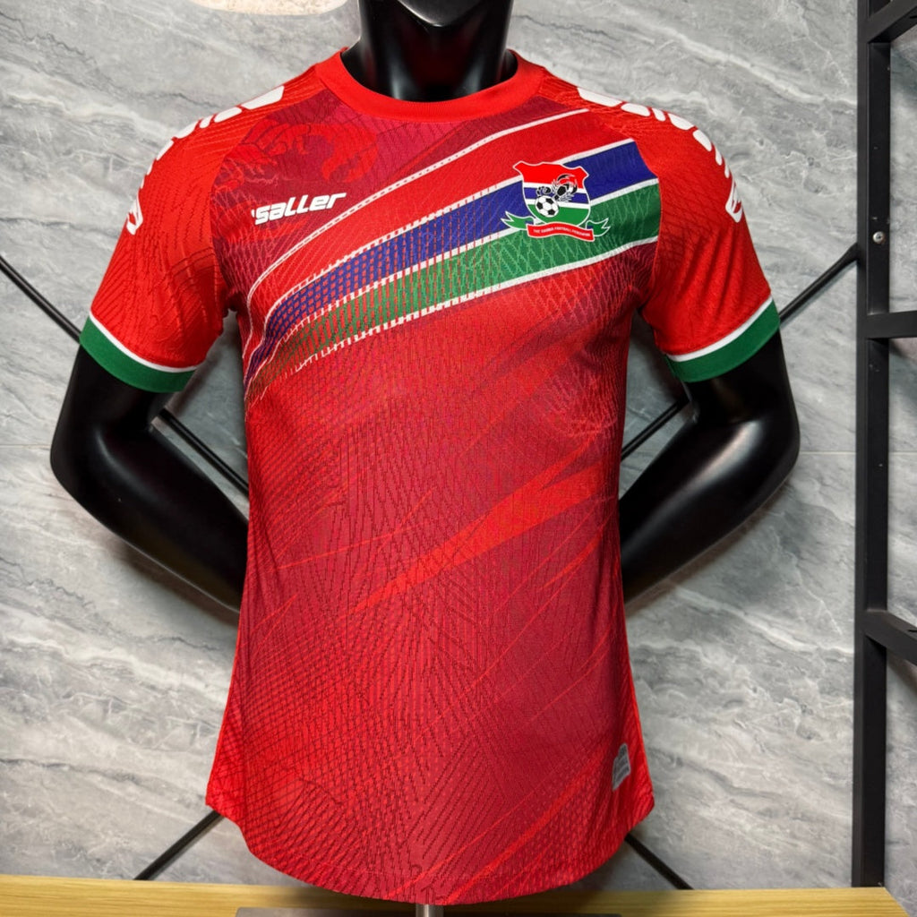 Maillot de football Le 12 -ème Maillot pour enfant 25/26 Gambia rouge, maillot de joueur avec logo et détails colorés.