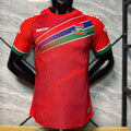 Maillot de football Le 12 -ème Maillot pour enfant 25/26 Gambia rouge, maillot de joueur avec logo et détails colorés.