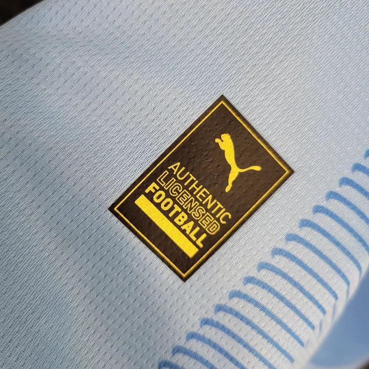 Maillot domicile Manchester City saison 2023-2024, marque Le 12 -ème Maillot, vue de face avec logo et détails du maillot.