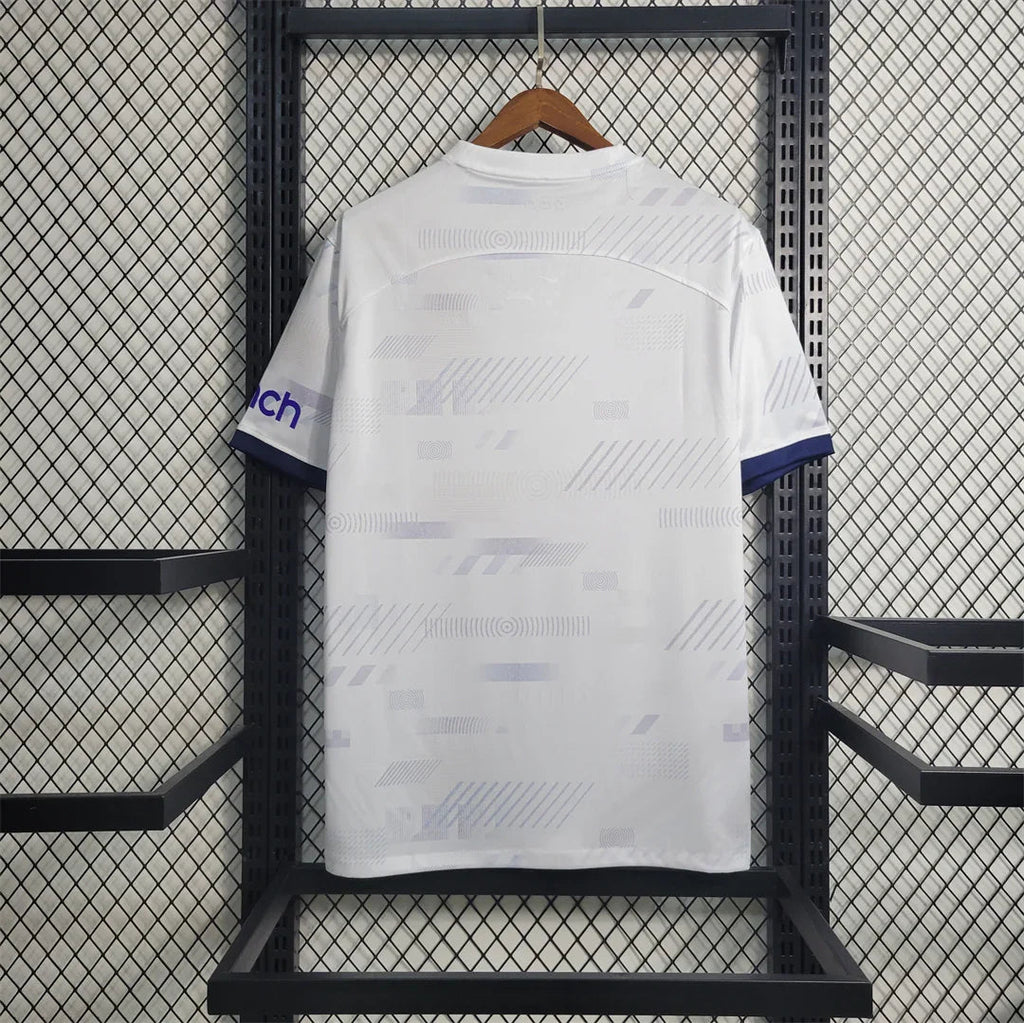 Maillot Tottenham 2023-24 Le 12 -ème Maillot, maillot de football avec logo et détails de l'équipe en tissu blanc et bleu.