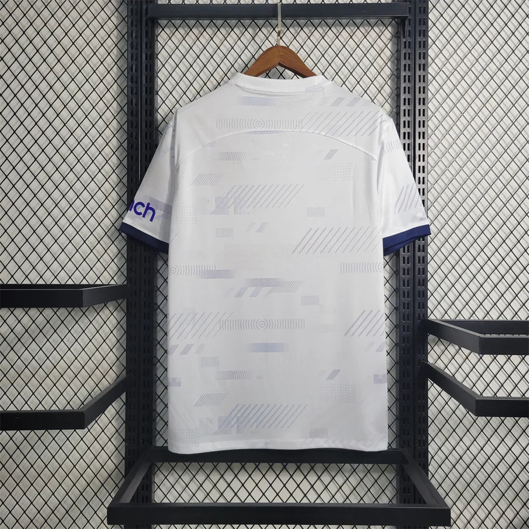 Maillot Tottenham 2023-24 Le 12 -ème Maillot, maillot de football avec logo et détails de l'équipe en tissu blanc et bleu.
