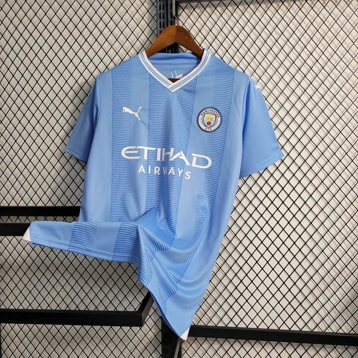 Maillot domicile Manchester City 2023-2024 de la marque Le 12-ème Maillot, vue du devant avec logo et design officiel.
