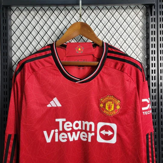 Maillot Manchester United 2023-2024 à manches longues, édition officielle Le 12-ème Maillot, logo et détails de l'équipe visibles.