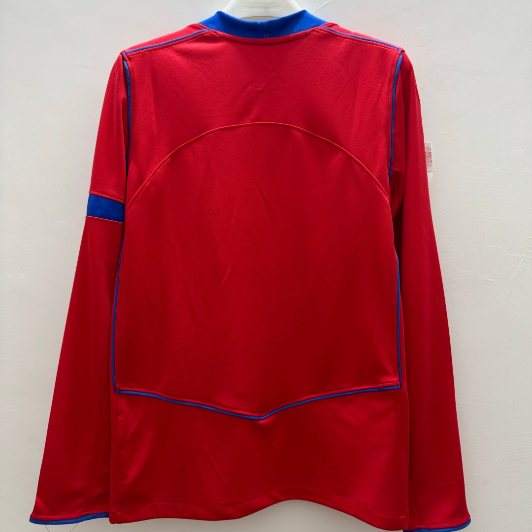 Maillot PSG troisième version à manches longues, marque Le 12-ème Maillot, en tissu bleu avec logo et détails rouges.