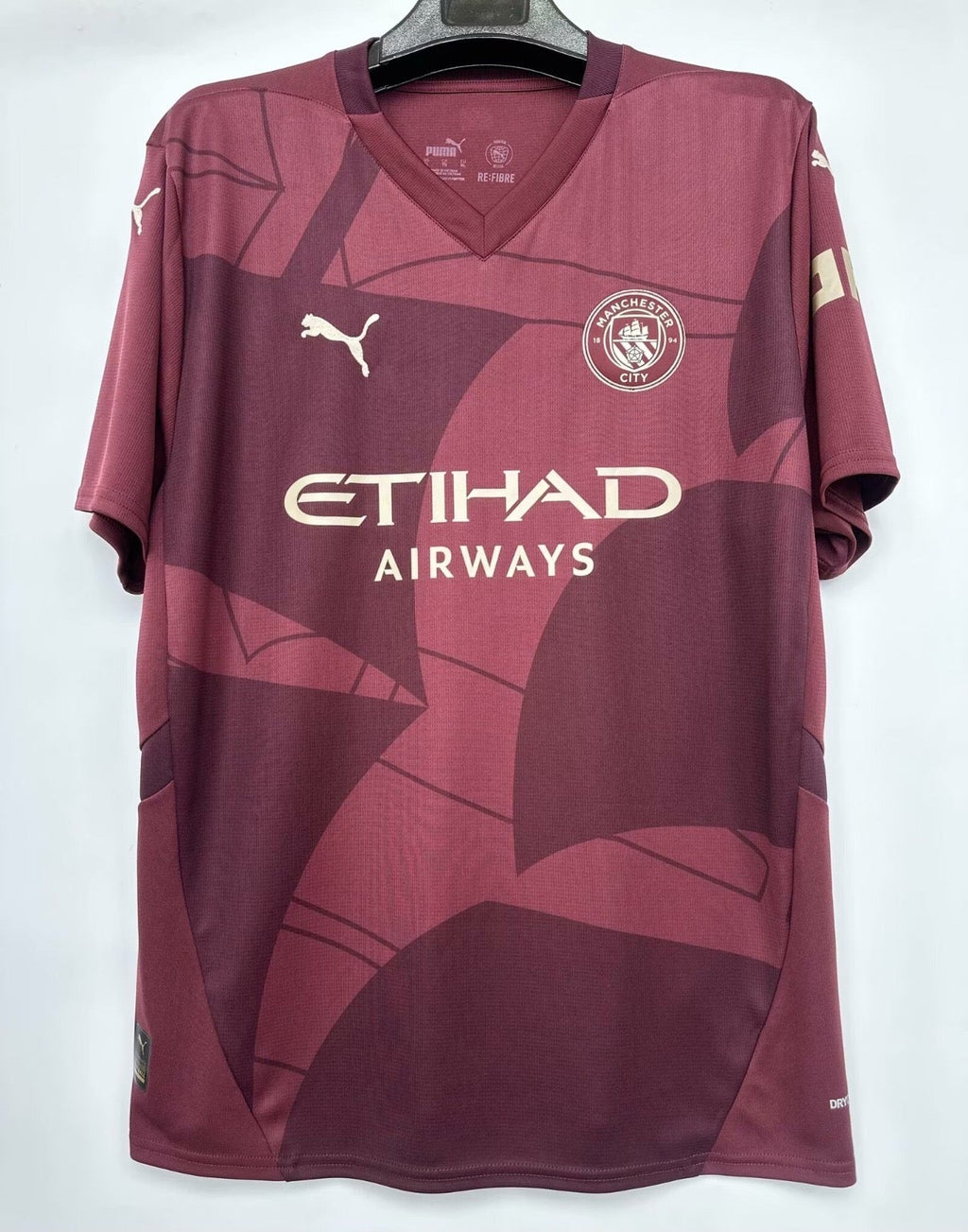 Maillot 24/25 Manchester City Le 12-ème Maillot rouge, maillot de football avec logo et détails du club.