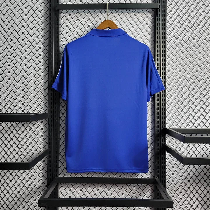 Maillot rétro de l'équipe de France 1985/86 Le 12, maillot de football bleu avec logo tricolore, vue de face.