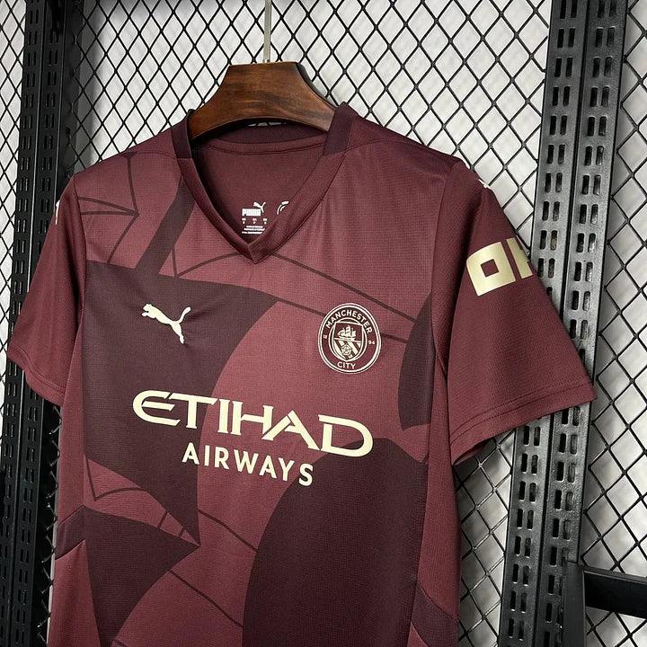 Maillot Manchester City 2024/25 Le 12 -ème Maillot, maillot de football bleu avec logo du club et détails blancs.