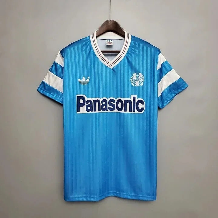 Maillot de football Marseille rétro extérieur 1990 de la marque Le 12-ème Maillot, avec logo et design vintage visible.
