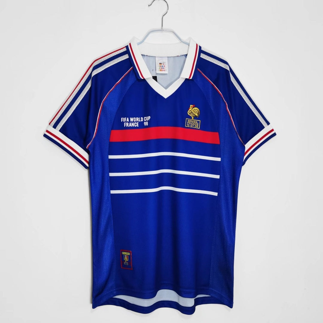 Maillot rétro de l'équipe de France 1998, marque Le 12 -ème Maillot, vue de face avec détails du design bleu et logo officiel.