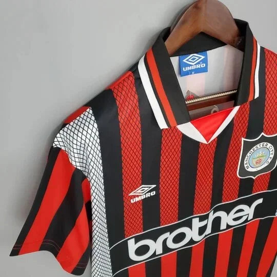 Maillot Manchester City rétro 94/96 de la marque Le 12-ème Maillot, vue de face avec logo et détails du design.