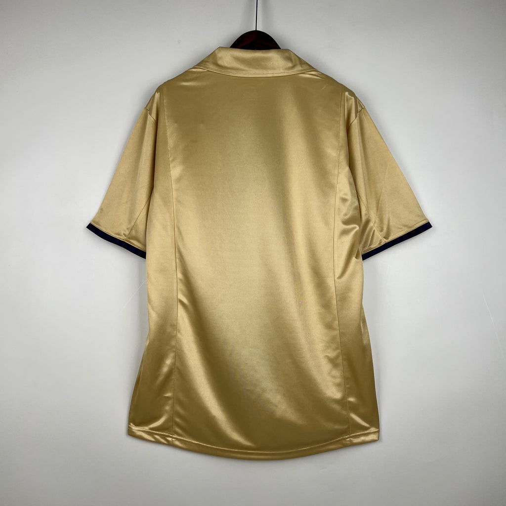 Maillot rétro FC Barcelone 2002, blanc avec logo blaugrana, manches bleues, porté par un supporter ou modèle.
