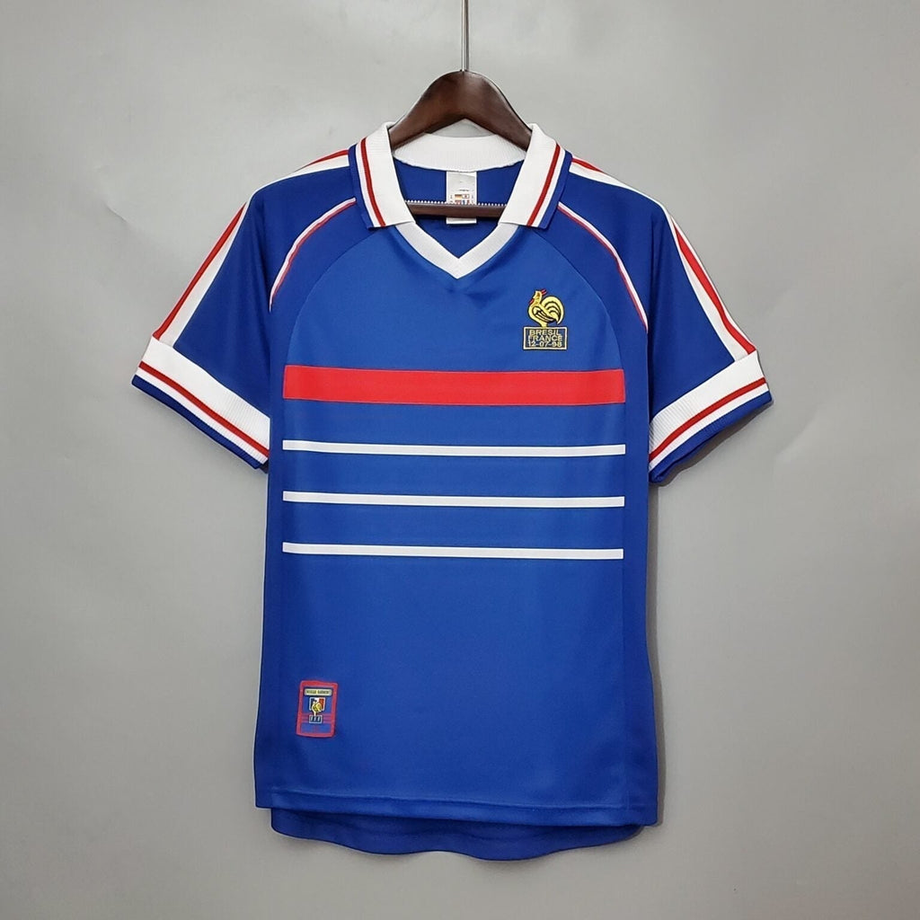 Maillot rétro de l'équipe de France 1998, signé Le 12 -ème Maillot, affiché avec détails du design bleu et logos.