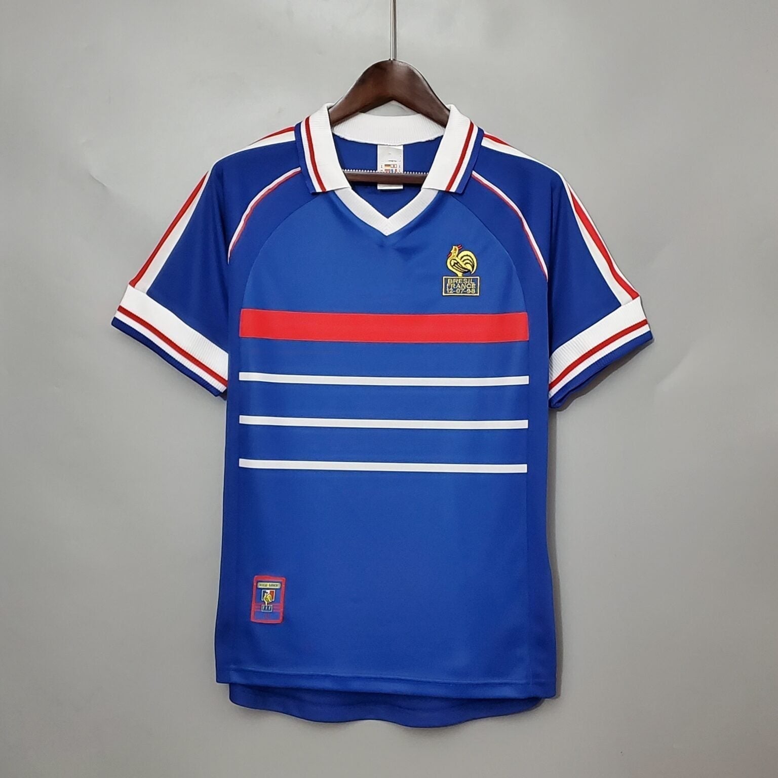 Maillot rétro de l'équipe de France 1998, signé Le 12 -ème Maillot, affiché avec détails du design bleu et logos.