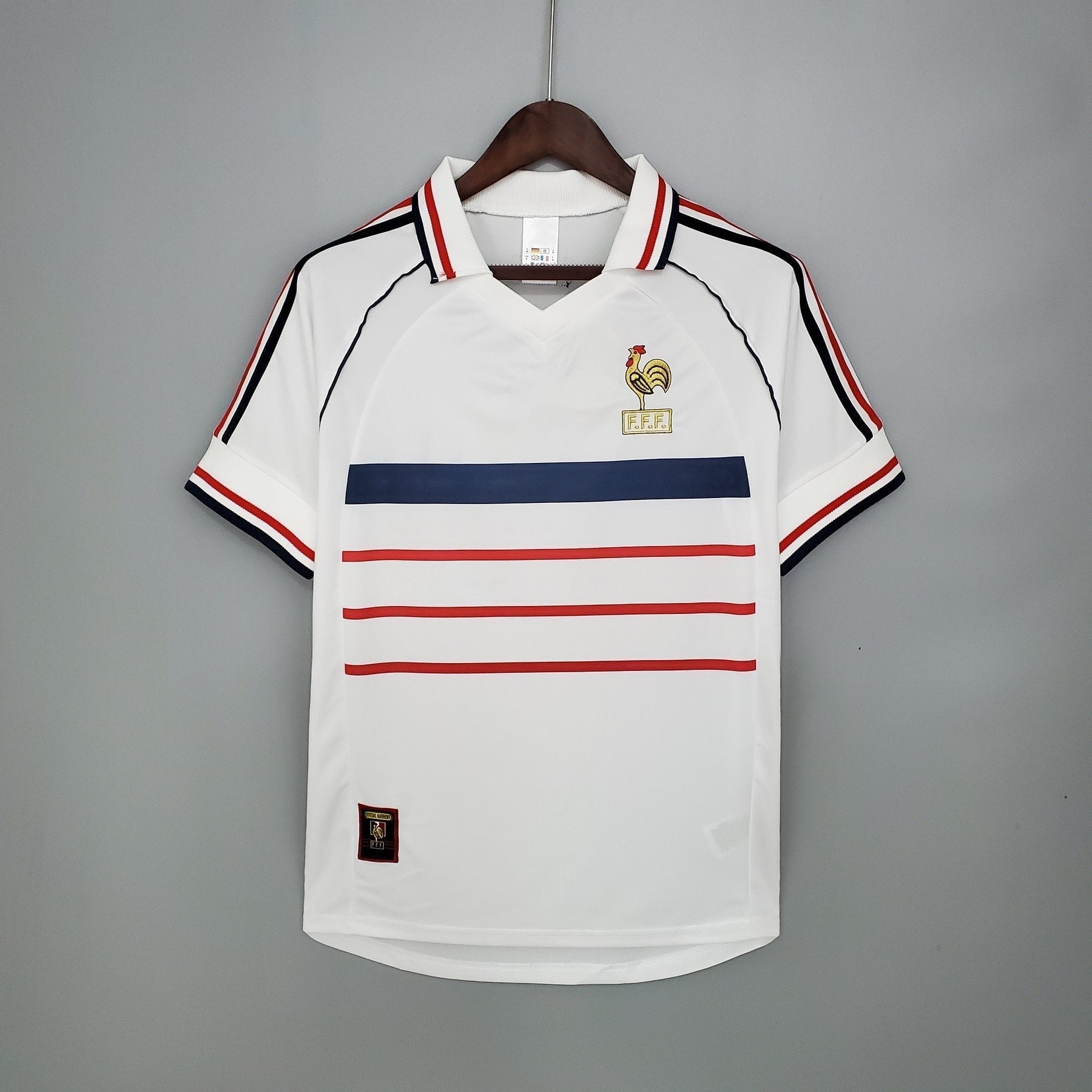 Maillot rétro de l'équipe de France 1998, marque Le 12 -ème Maillot, avec logo et design authentique visible sur le vêtement.