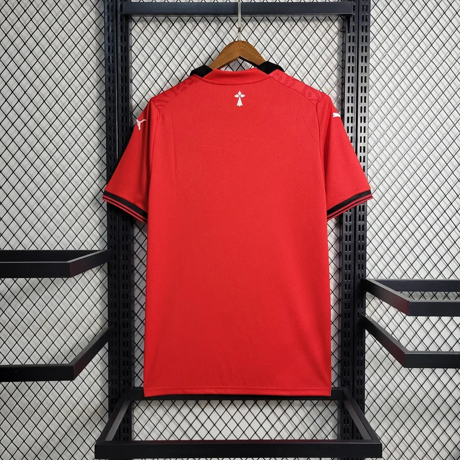 Maillot domicile Le 12 -ème Maillot pour Rennes 2023/24, maillot de football rouge avec logo et détails sportifs visibles.