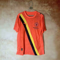 Maillot Manchester City 2025-2026, orange, en tissu léger, porté par un mannequin, avec logo et détails du club.