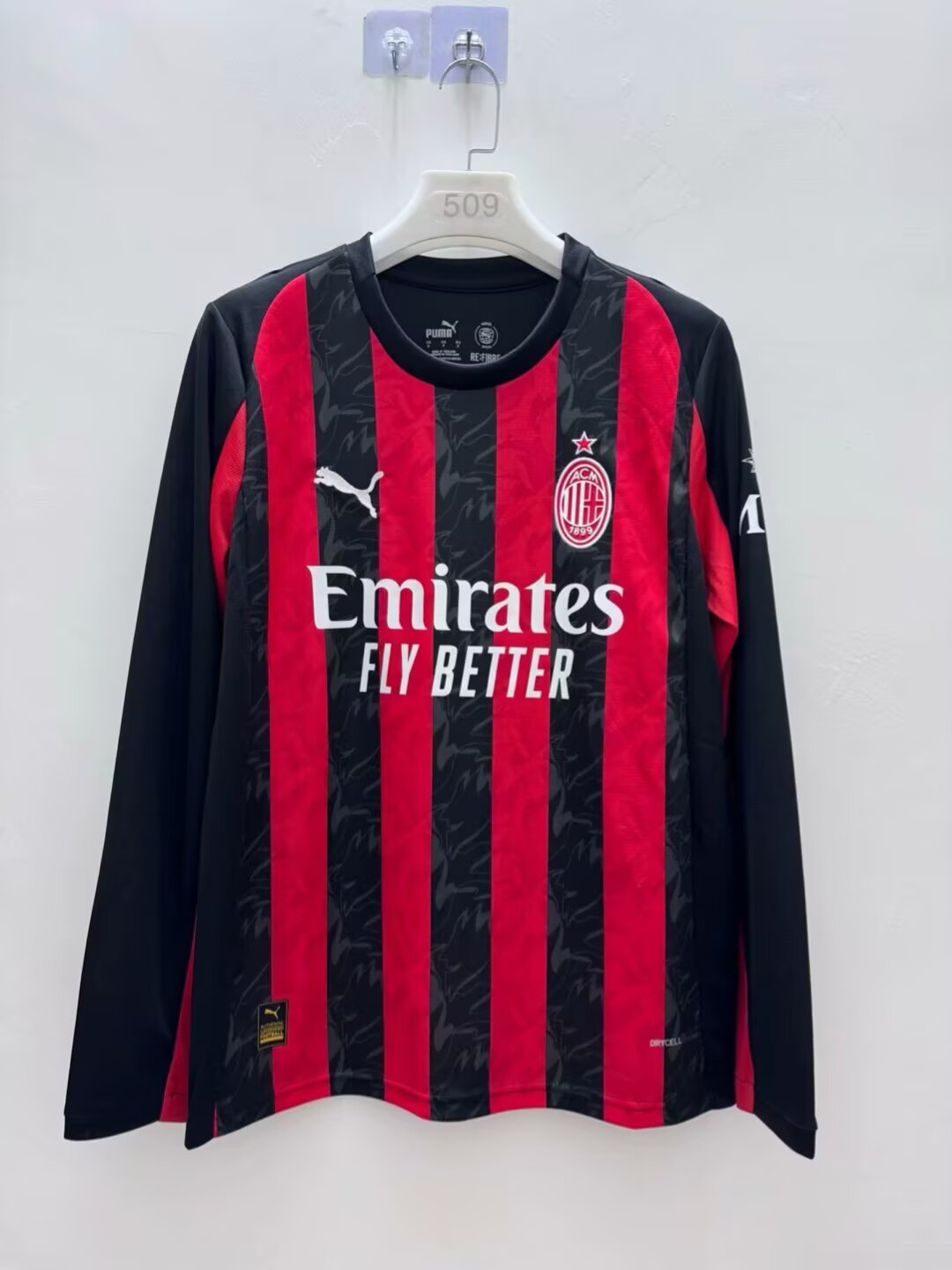 Maillot à manches longues AC Milan pour enfants 25/26, marque Le 12, en tissu bleu avec le logo du club visible.