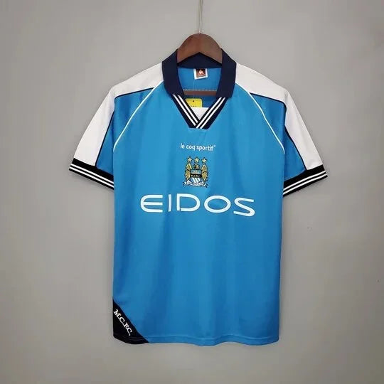Maillot rétro Manchester City 99/01 de la marque Le 12-ème, vue en gros plan avec logo et détails du maillot.