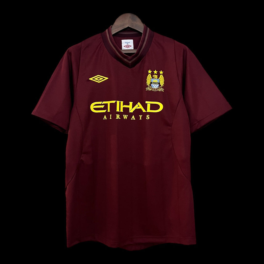 Maillot Manchester City 12/13 rétro de la marque Le 12 -ème Maillot, vue de face avec logo et détails du maillot.