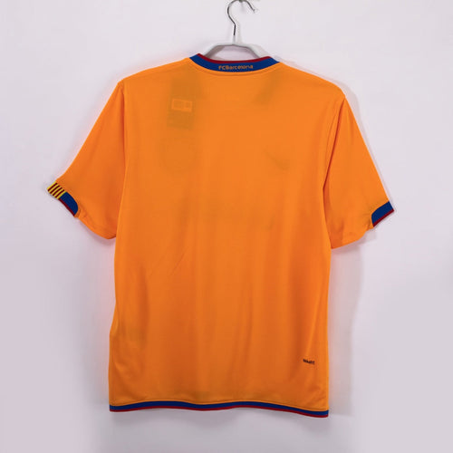 Maillot extérieur rétro du FC Barcelone 2006-2007, marque Le 12, en tissu bleu avec logo et détails du club.