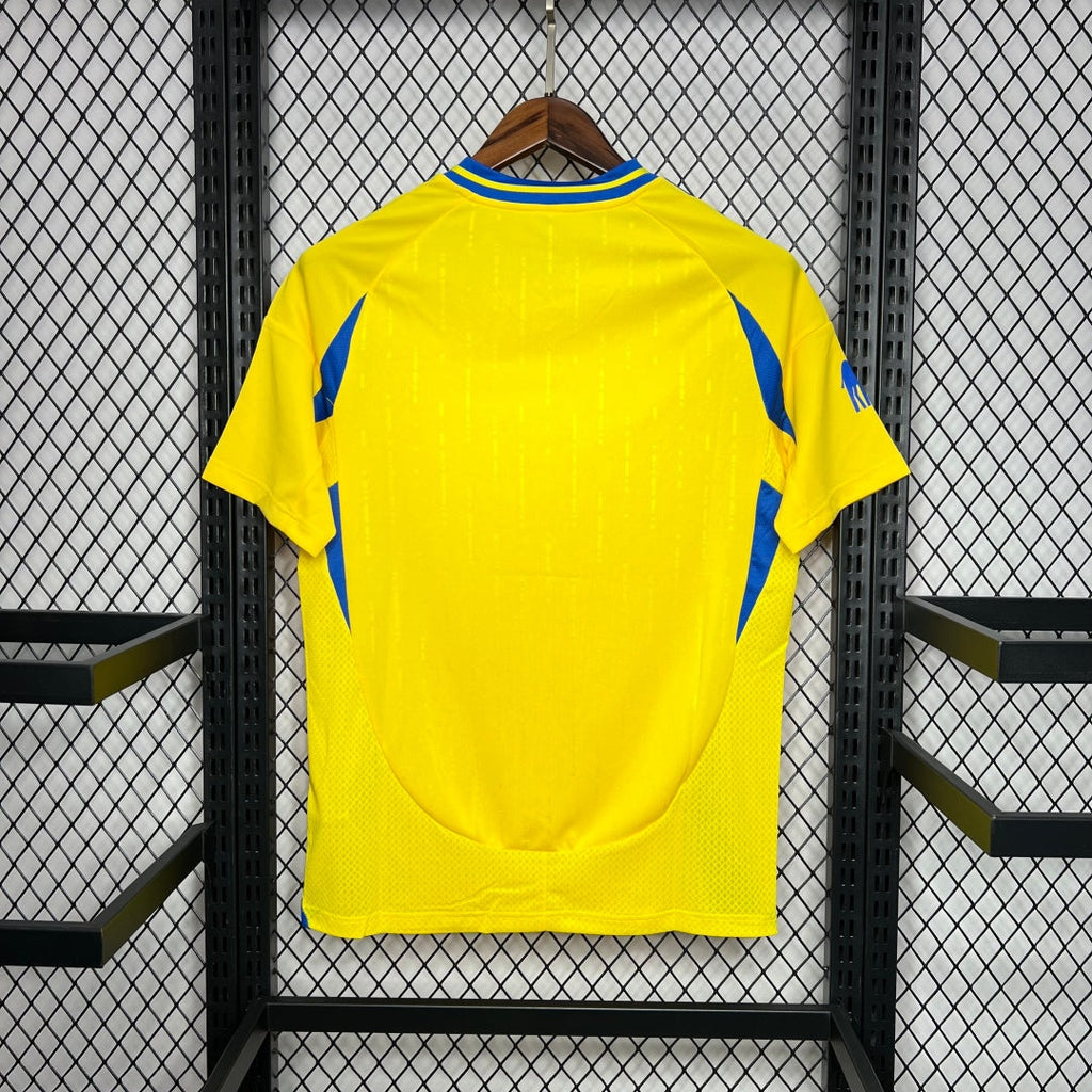 Maillot domicile 24/25 AL-NASSR Le 12-ème, maillot de football rouge avec logo et détails colorés, vue frontale.