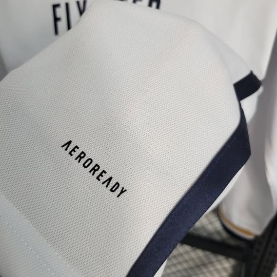 Maillot à manches longues Real Madrid 2023-2024, marque Le 12 -ème Maillot, en tissu blanc avec logo et détails en bleu.