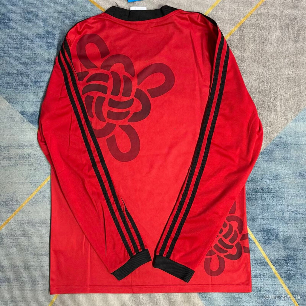 Maillot Manchester United 25/26 manches longues Le 12-ème Maillot, maillot de football rouge avec logo et détails du club.