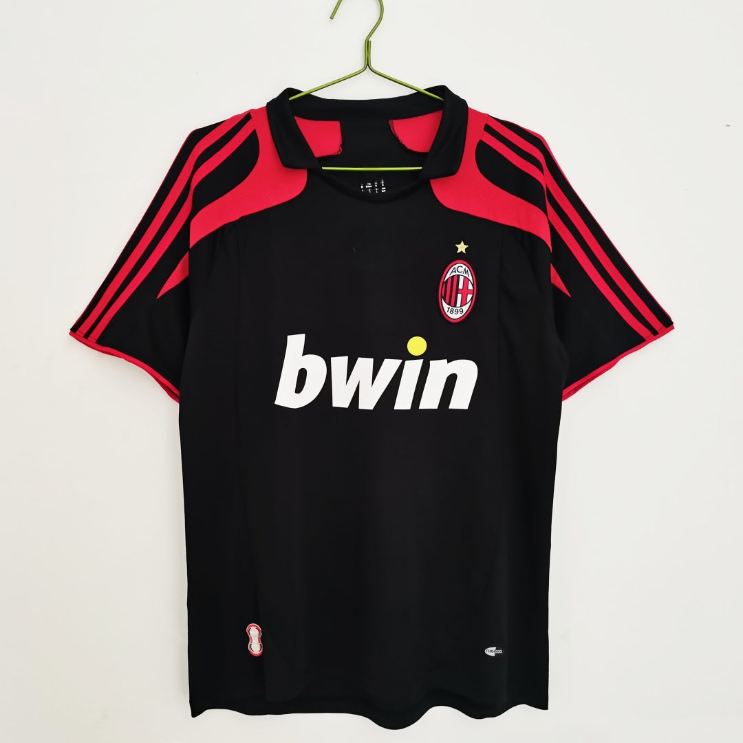 Maillot rétro third de 2007-2008 de l'AC Milan, marque Le 12, avec logo et design orange et noir, vue de face.