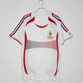 Maillot rétro extérieur de l'équipe de France 2006, marque Le 12 -ème Maillot, avec design vintage et couleurs bleu, blanc et rouge.