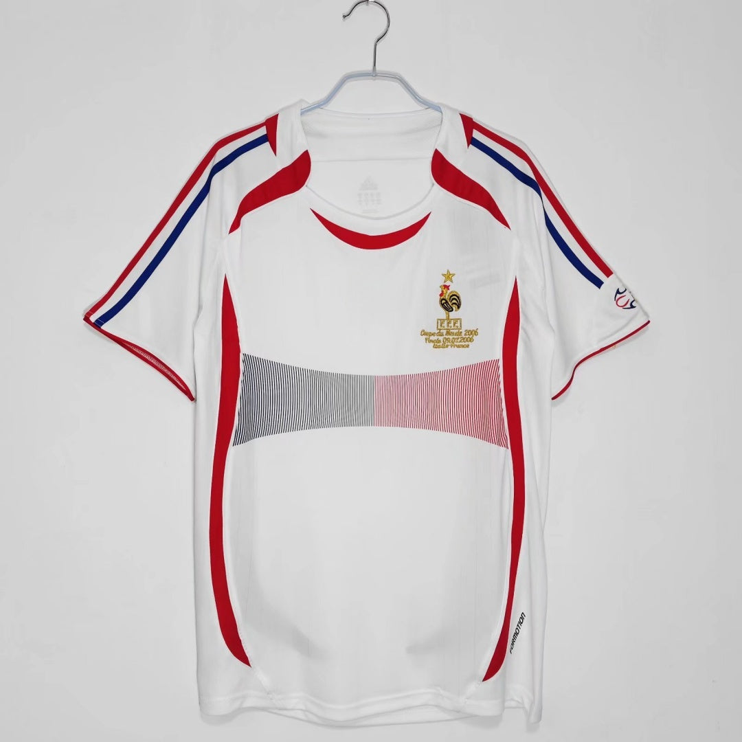 Maillot rétro extérieur de l'équipe de France 2006, marque Le 12 -ème Maillot, avec design vintage et couleurs bleu, blanc et rouge.