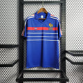 Maillot rétro de l'équipe de France 1985/86 de la marque Le 12, maillot de football vintage avec logo et design d'époque.