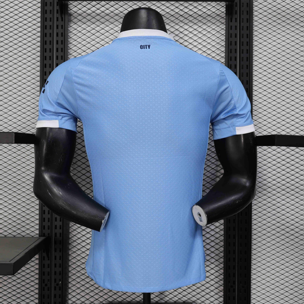 Maillot Manchester City 25-26 ans, marque Le 12 -ème Maillot, vue de face avec logo et détails en bleu et blanc.