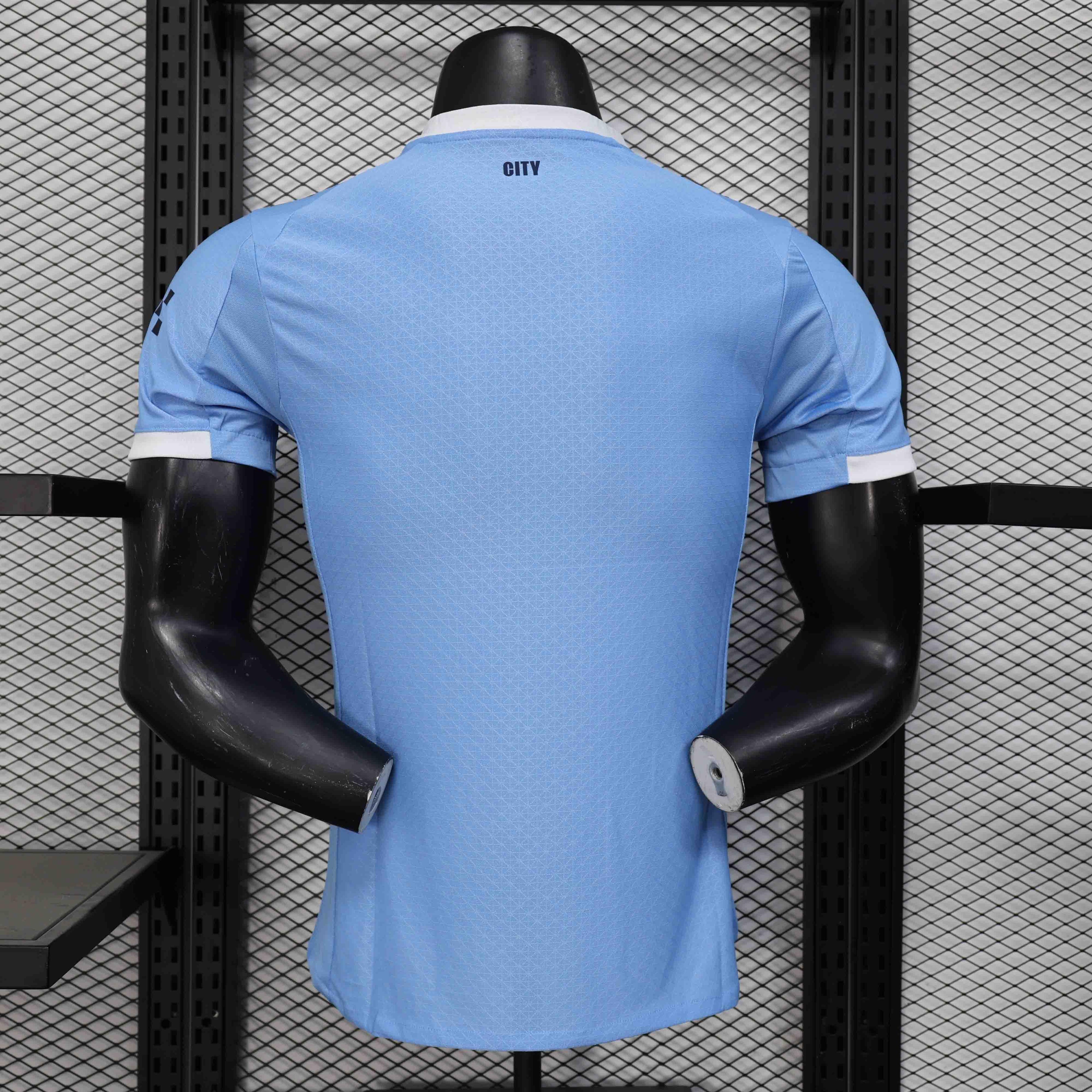 Maillot Manchester City 25-26 ans, marque Le 12 -ème Maillot, vue de face avec logo et détails en bleu et blanc.