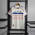 Maillot rétro de l'équipe de France 1998, rouge avec logo et détails en bleu, porté par un mannequin.