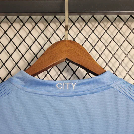 Maillot Manchester City 2023 2024 à manches longues, par Le 12 -ème Maillot, vue de face avec logo et motifs bleus.