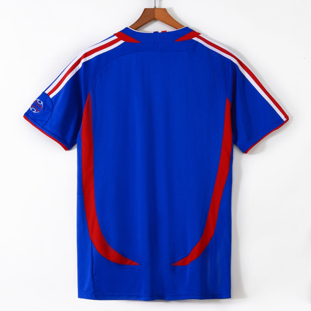 Maillot rétro domicile France 2006, marque Le 12-ème Maillot, vue de face avec logo et détails bleus et rouges sur fond blanc.